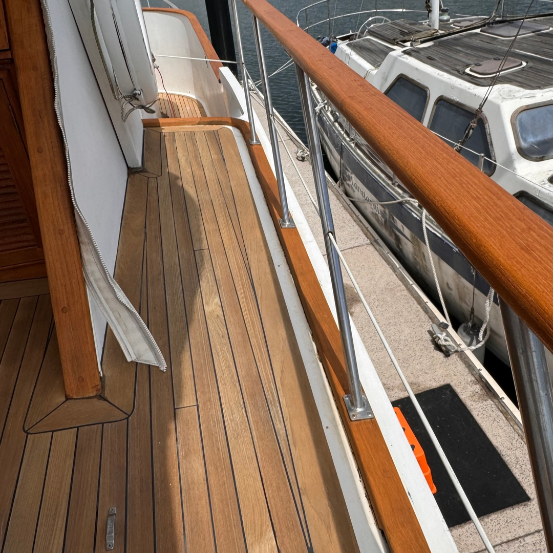 Wooden deck of a boat with railing which has recently had Semco Teak Cleaner applied. 