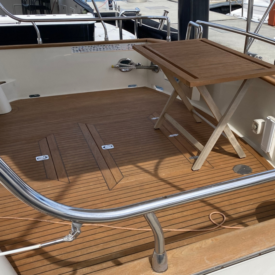 A boat's aft teak deck with a small table, which has a new coat of Semco Honeytone Teak Sealer for protection.