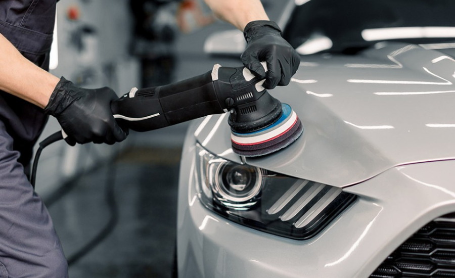 Person polishing a car's headlight with a polisher